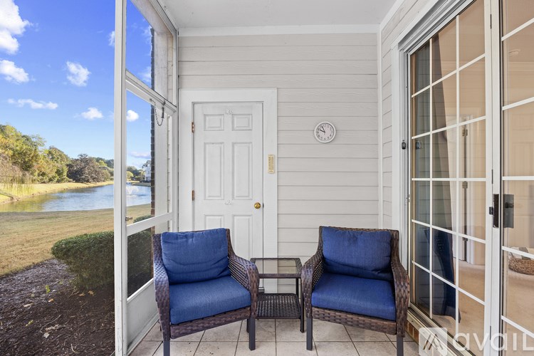 Two chairs are on a porch with a view of a river.