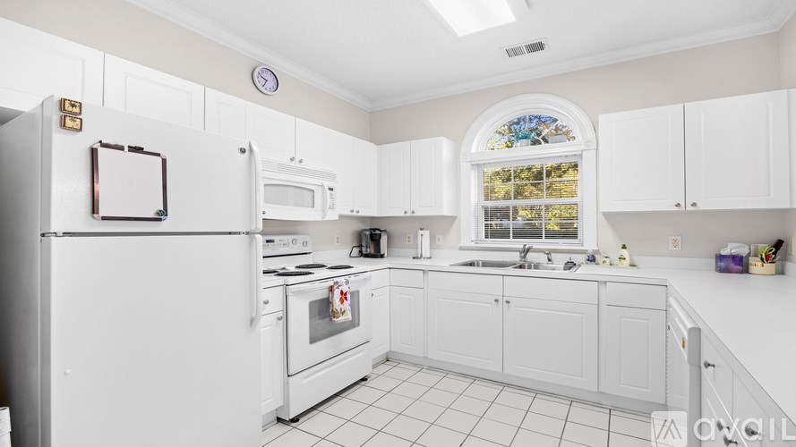 A white kitchen with a stove top oven and a microwave.