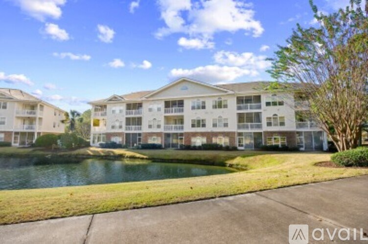 A large apartment complex with a pond in front.