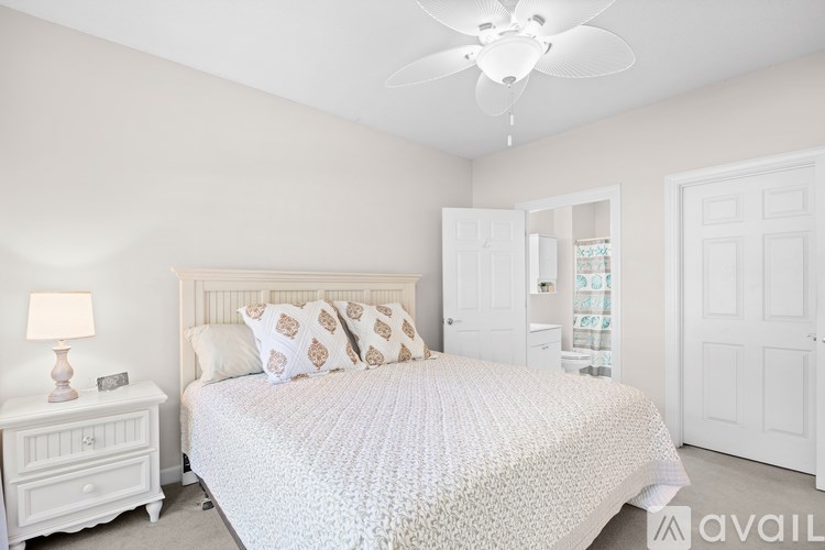 A bedroom with a large bed and a ceiling fan.