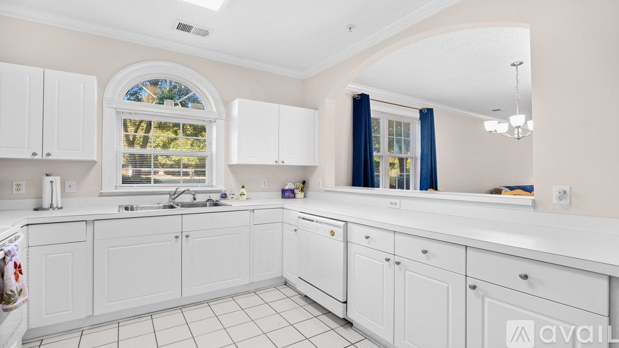 A kitchen with white cabinets and a window with blue curtains.