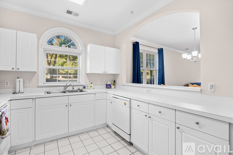 A kitchen with white cabinets and a window with blue curtains.