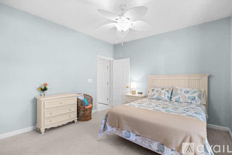 A bedroom with a bed, dresser, and ceiling fan.