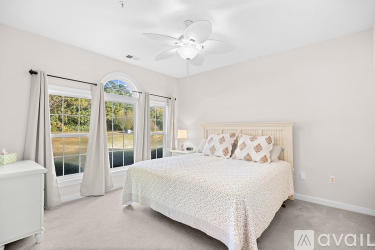 A bedroom with a large bed and a ceiling fan.