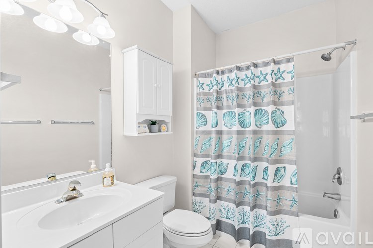 A bathroom with a white sink, toilet, and shower curtain.