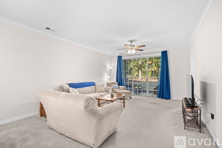 A living room with a beige couch and a ceiling fan.