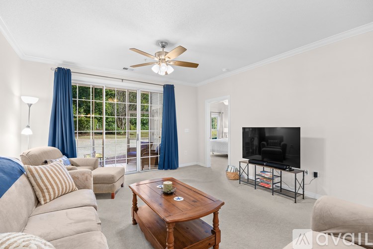 A living room with a television, a sofa, a coffee table, and a ceiling fan.