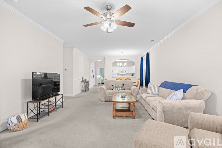 A living room with a television, couches, and a ceiling fan.