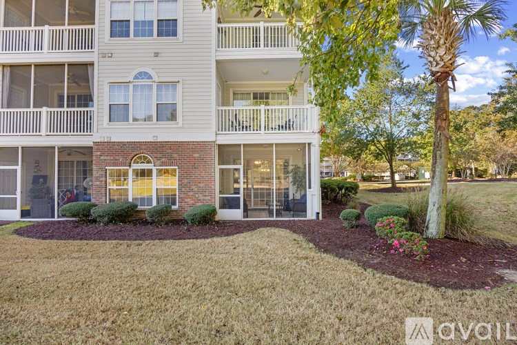 A building with a balcony and a tree in front.