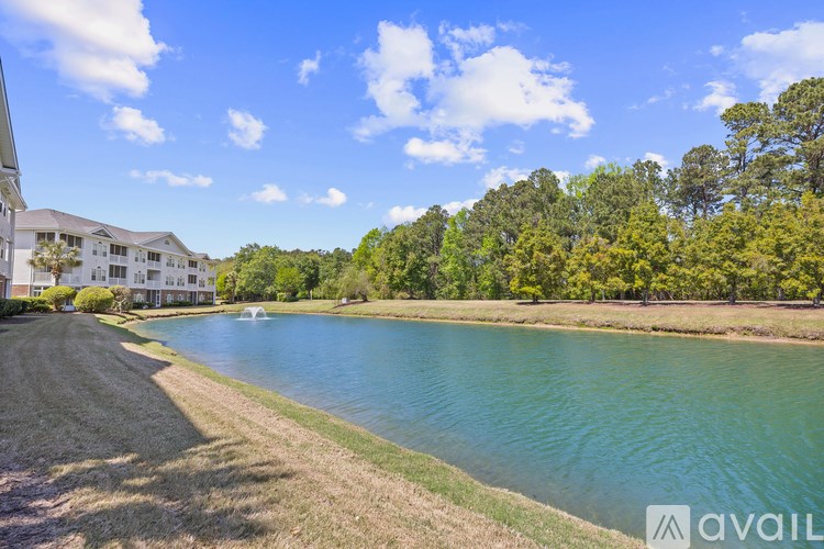 A serene lake surrounded by trees and a building on the left.