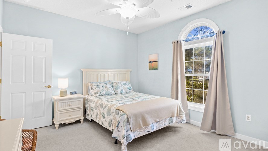 A bedroom with a large bed, a dresser, and a window with curtains.
