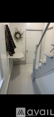 A hallway with a coat rack and a wreath on the door.