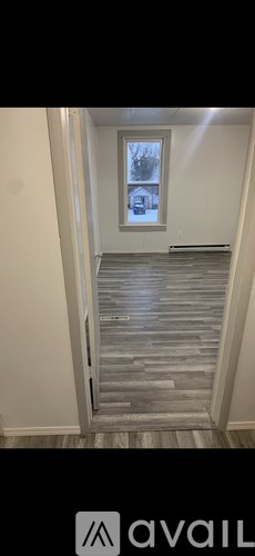 A hallway with a wooden floor and a window.