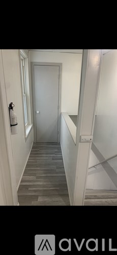 A hallway with a grey door and a white wall.