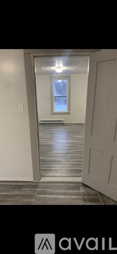 A hallway with a light on and a door at the end.