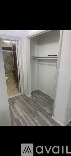 A white closet with a shelf and a door leading to a bathroom.