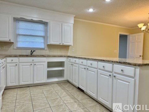 A kitchen with white cabinets and a granite countertop.