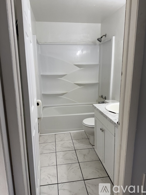 A white bathroom with a toilet, sink, and shelves.