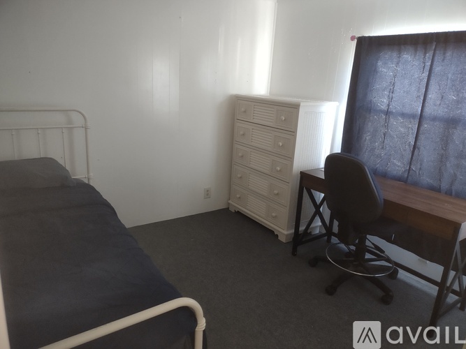 A bedroom with a bed, chair, and dresser.