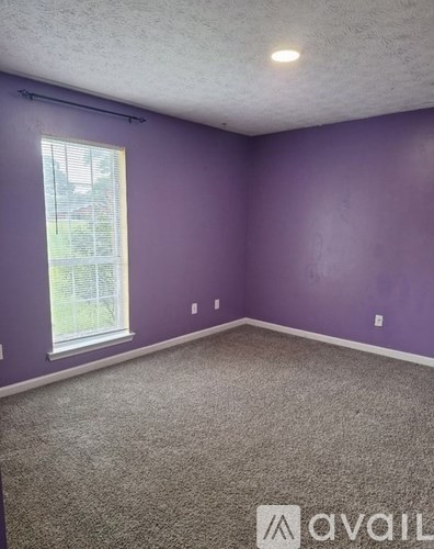 A room with purple walls and a window with blinds.