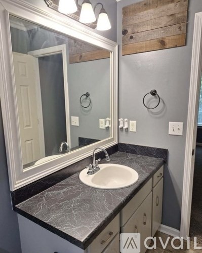 A bathroom with a marble countertop and a large mirror.