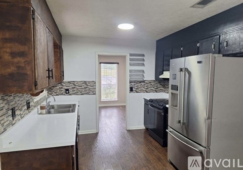 A kitchen with a refrigerator, sink, and cabinets.
