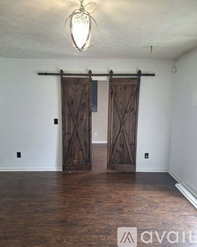 A room with a sliding barn door and wood flooring.