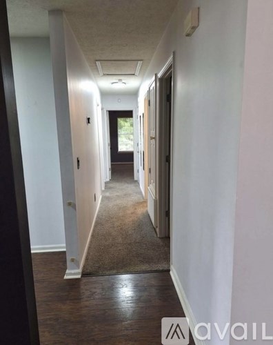 A hallway with a carpeted floor and white walls.