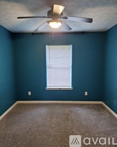 A room with a ceiling fan and a window with blinds.