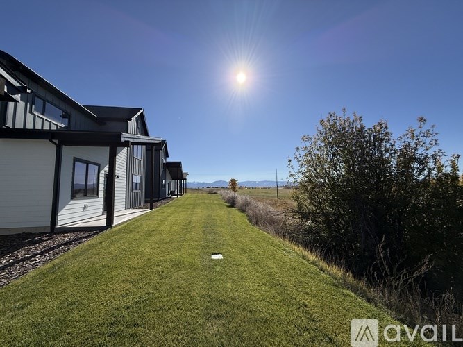 A sunny day with a house and a green lawn in the foreground.