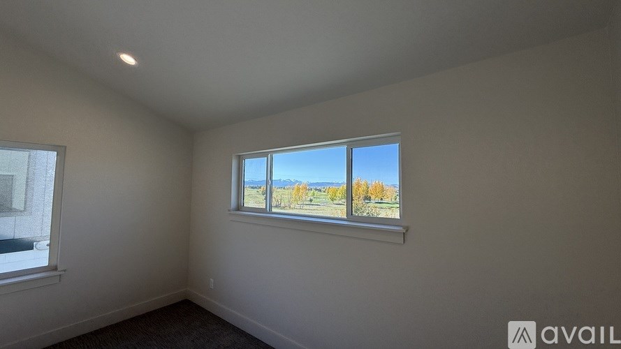 A room with a window showing a view of trees and sky.