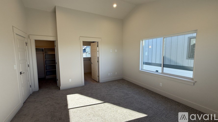 A room with a carpeted floor and a window with a view of a building outside.