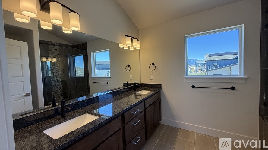 A bathroom with a large mirror, two sinks, and a window.