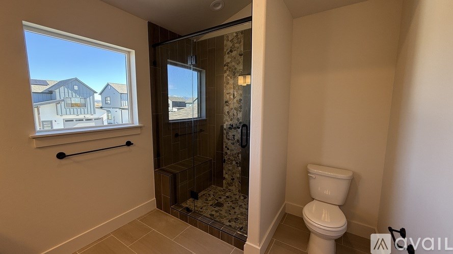 A bathroom with a toilet, a window, and a shower.