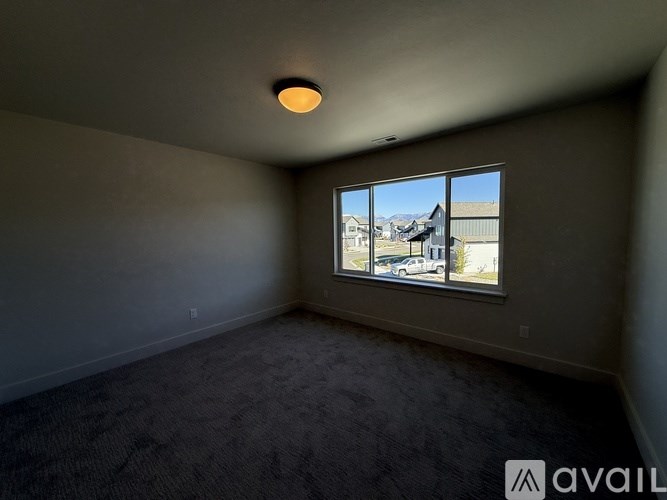 A room with a carpeted floor and a window showing a view of buildings outside.