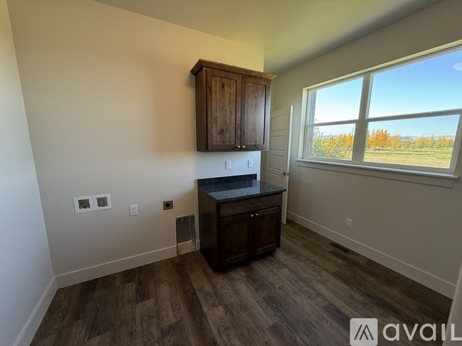A kitchen area with wooden cabinets and a window overlooking a field.