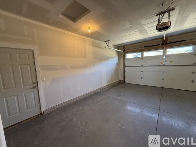 A room with a white door and a window with a garage door opener.