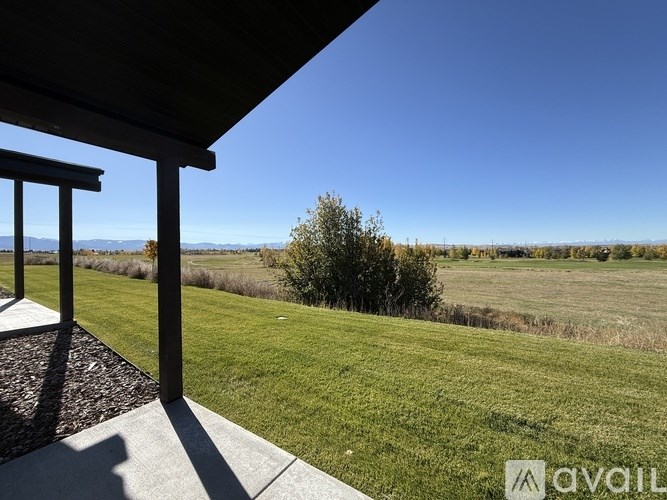 A view from a covered porch looking out over a grassy field.