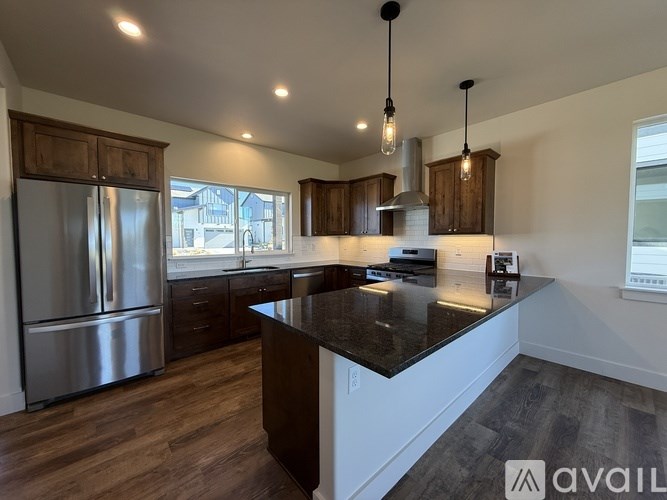 A modern kitchen with dark wood floors and stainless steel appliances.