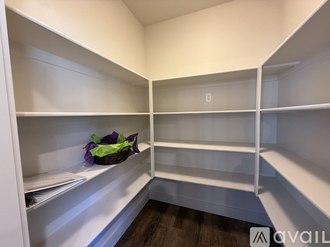 Empty white shelves in a room with a basket of lettuce on the left.