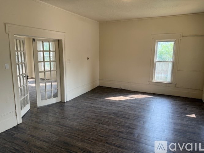 A room with wooden floors and two windows.