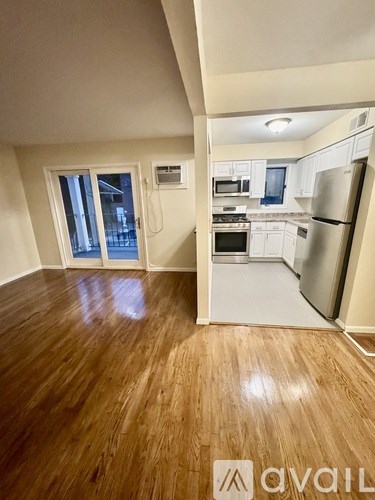 A kitchen with white cabinets and a refrigerator in a room with wooden floors.
