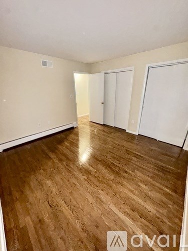 A room with wooden flooring and white walls.