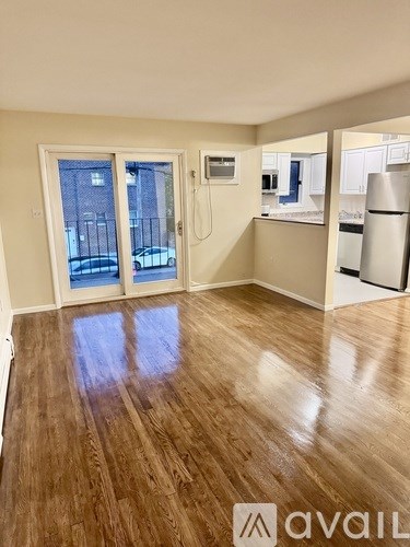 A room with wooden flooring and a refrigerator in the corner.