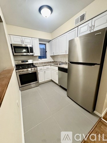 A kitchen with a stainless steel refrigerator and white cabinets.