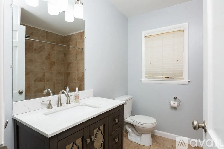 A bathroom with a toilet, sink, and mirror.