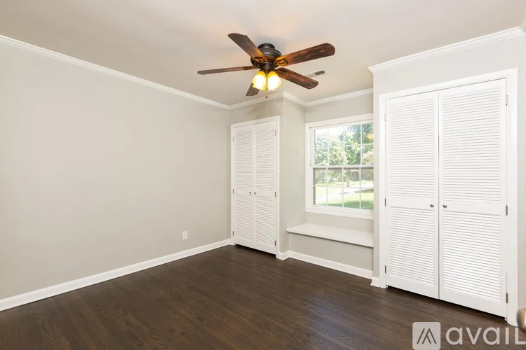 A room with a ceiling fan and a window with white shutters.