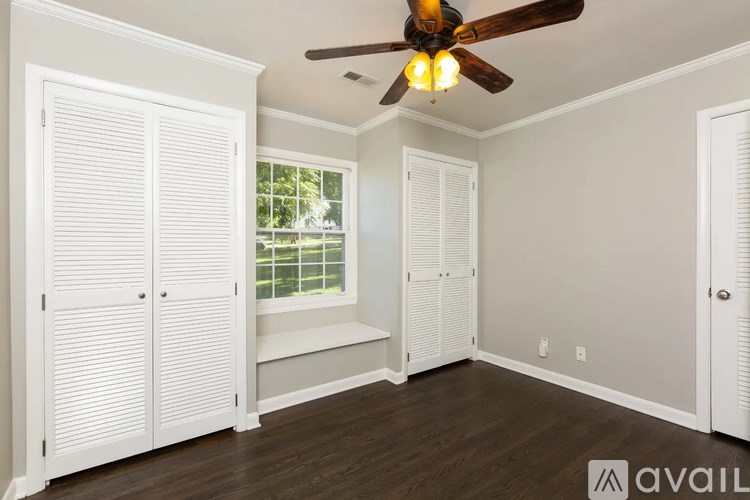A room with a ceiling fan and a window with white shutters.