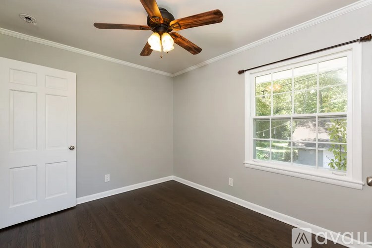 A room with a ceiling fan and a window with a view of a tree.