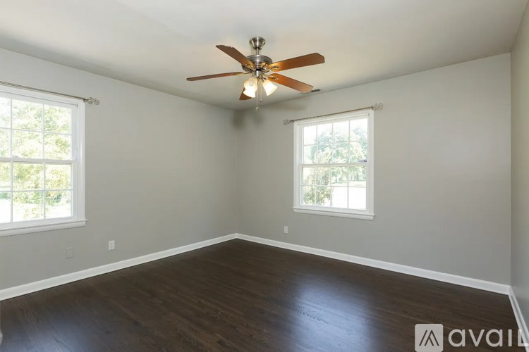 A room with a ceiling fan and two windows.